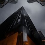 A low angle view of skyscrapers reaching into a moody night sky, representing foundation and building growth marketing strategy for startups